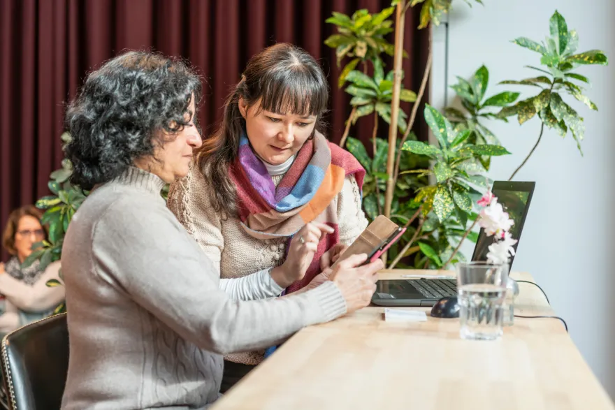 Freiwillige unterstützt Teilnehmende des Digital-Cafés 2.0 bei der Nutzung Ihres Smartphones.